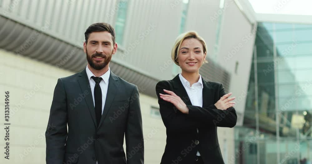 Caucasian young good looking man and woman, business partners giving five to each other like havinga deal, then smiling to the camera. Outside. Portrait. Caucasian young good looking man and woman, business partners giving five to each other like havinga deal, then smiling to the camera. Outside. Portrait.