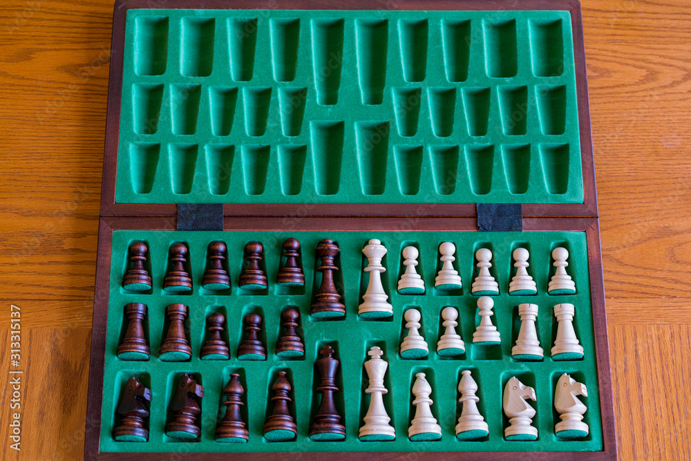 A wooden chess set in its box, view from above with brown background. The picture shows old traditional hand-made chess in a box A wooden chess set in its box, view from above with brown background. The picture shows old traditional hand-made chess in a box