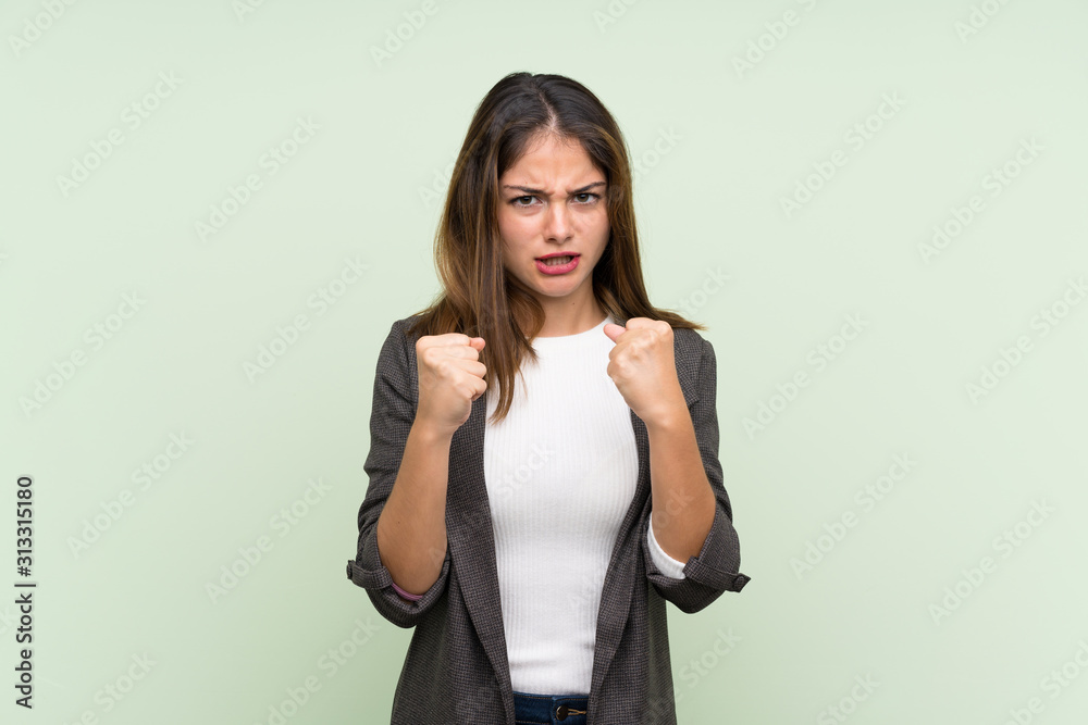 Young brunette girl with blazer over isolated green background frustrated by a bad situation Young brunette girl with blazer over isolated green background frustrated by a bad situation