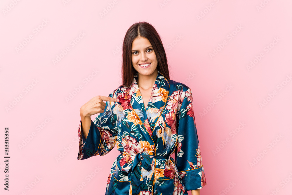 Young caucasian woman wearing a kimono pajama person pointing by hand to a shirt copy space, proud and confident Young caucasian woman wearing a kimono pajama person pointing by hand to a shirt copy space, proud and confident
