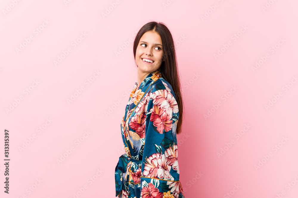 Young caucasian woman wearing a kimono pajama looks aside smiling, cheerful and pleasant. Young caucasian woman wearing a kimono pajama looks aside smiling, cheerful and pleasant.