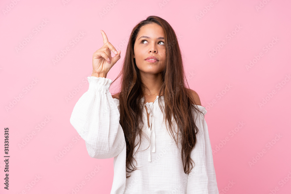 Young Brazilian girl over isolated pink background intending to realizes the solution while lifting a finger up Young Brazilian girl over isolated pink background intending to realizes the solution while lifting a finger up
