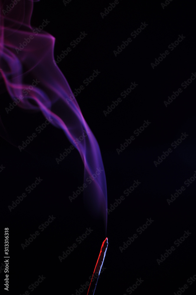 lilac smoke incense sticks on a black background. abstract figures of blue smoke on a black background