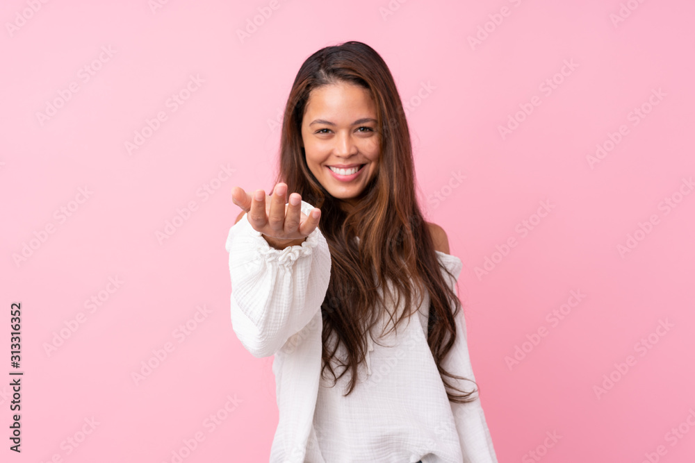 Young Brazilian girl over isolated pink background inviting to come with hand. Happy that you came Young Brazilian girl over isolated pink background inviting to come with hand. Happy that you came