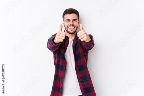 Young caucasian man posing in a white background isolated with thumbs ups, cheers about something, support and respect concept.