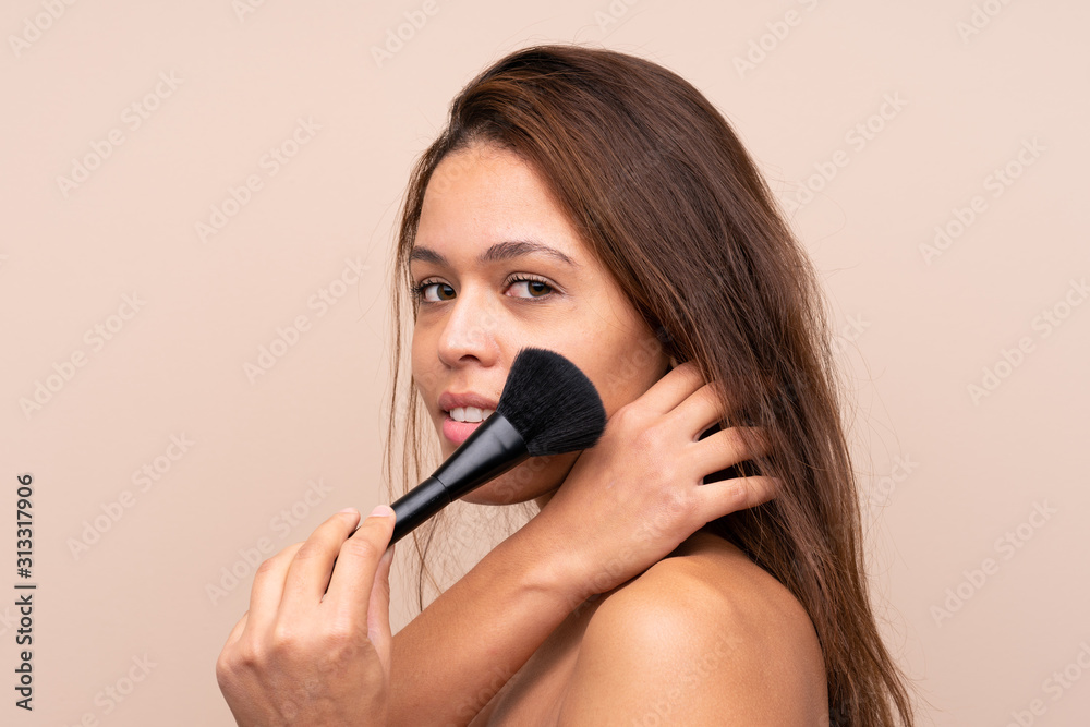 Young Brazilian girl with makeup brush over isolated background Young Brazilian girl with makeup brush over isolated background