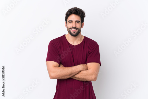 Young handsome man with beard over isolated white background keeping the arms crossed in frontal position