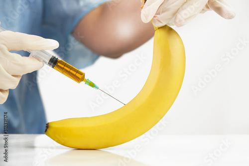 Foto Closeup of needle injected into banana fruit, Genetically engineered food concep
