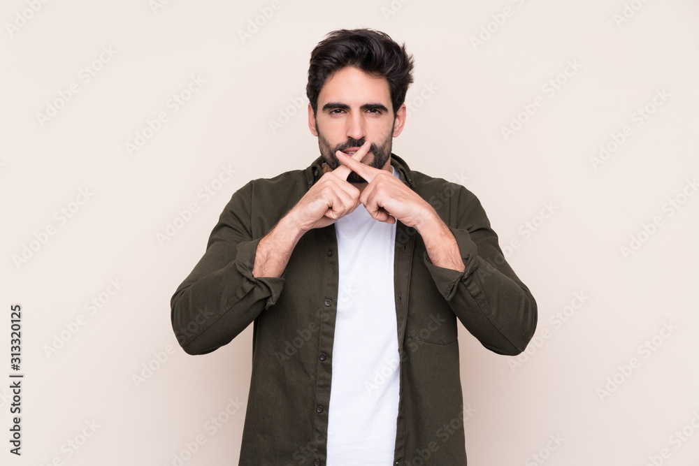 Young handsome man with beard over isolated background showing a sign of silence gesture Young handsome man with beard over isolated background showing a sign of silence gesture