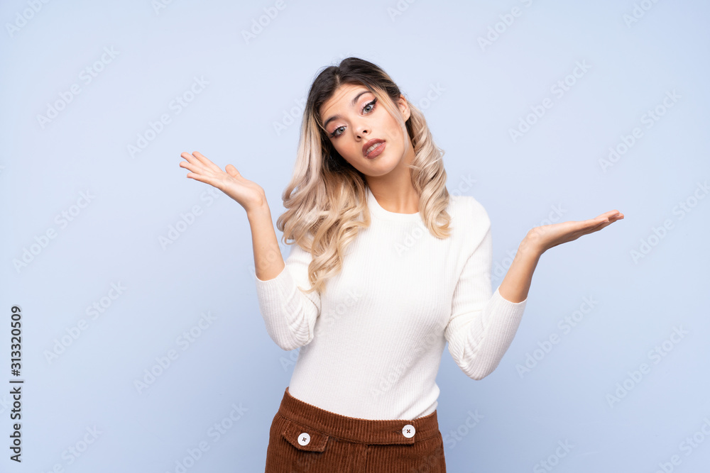 Young teenager girl over isolated blue background making doubts gesture Young teenager girl over isolated blue background making doubts gesture