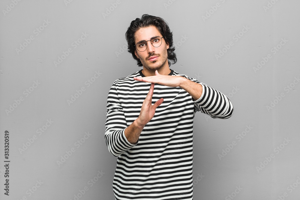 Young employee man holding an inventory showing a timeout gesture. Young employee man holding an inventory showing a timeout gesture.