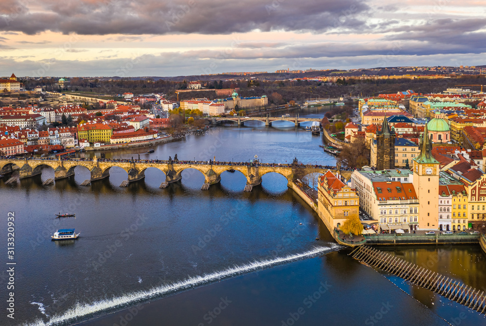 Prague, Czech Republic - Aerial panoramic drone view of the world famous Charles Bridge (Karluv most) and St. Francis Of Assisi Church with a beautiful winter sunset and sky