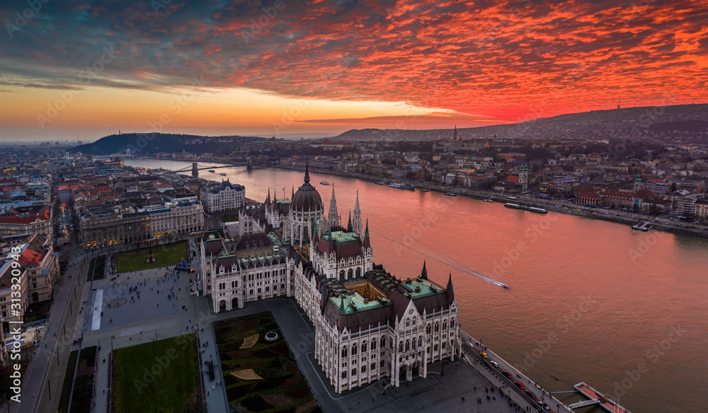 Obraz premium Budapest, Hungary - Aerial panoramic drone view of the Hungarian Parliament building on a winter afternoon with an amazing dramatic colorful gold and red sunset sky