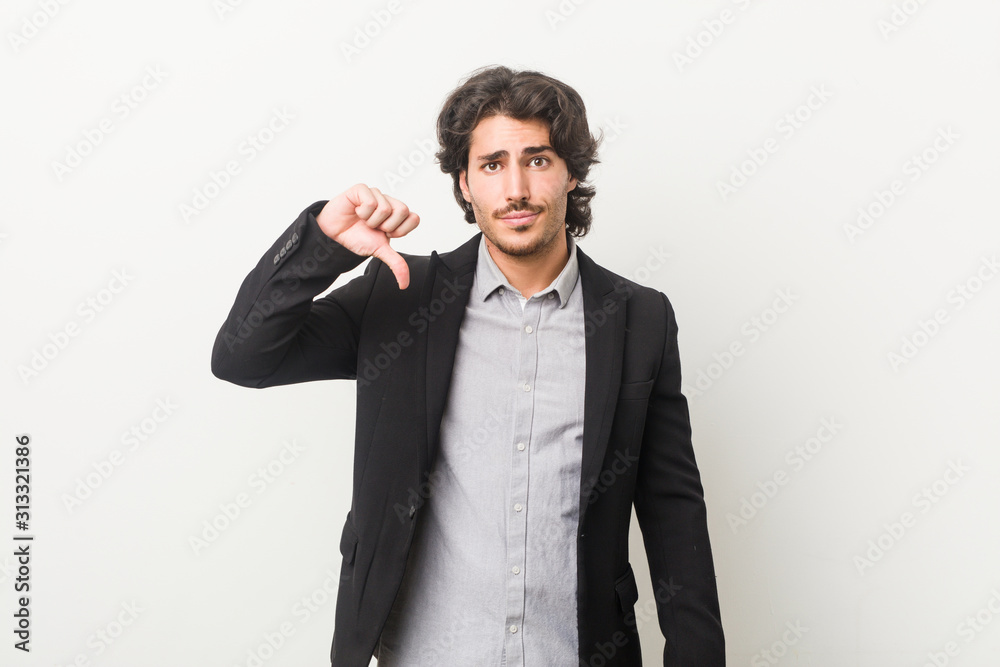 Young business man against a white background showing a dislike gesture, thumbs down. Disagreement concept. Young business man against a white background showing a dislike gesture, thumbs down. Disagreement concept.