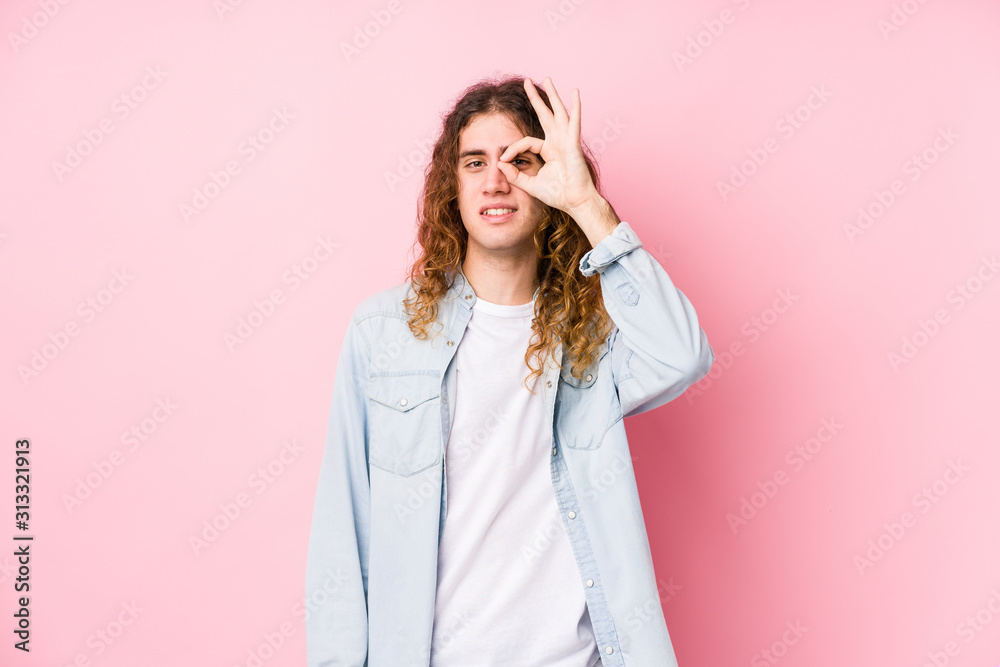 Long hair man posing isolated excited keeping ok gesture on eye. Long hair man posing isolated excited keeping ok gesture on eye.