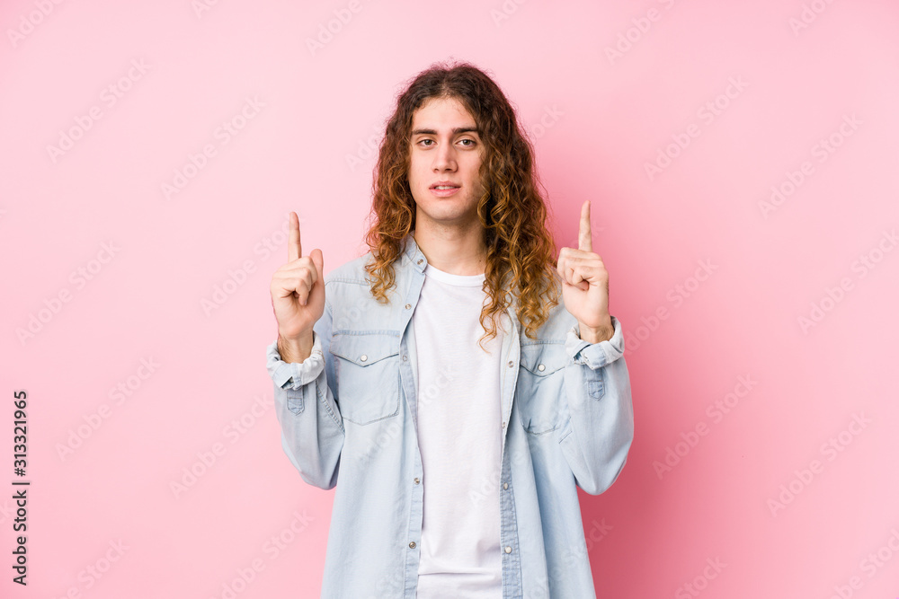 Long hair man posing isolated indicates with both fore fingers up showing a blank space. Long hair man posing isolated indicates with both fore fingers up showing a blank space.