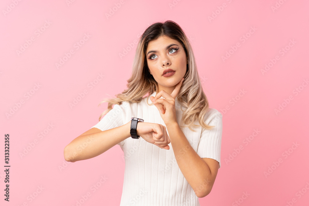 Teenager girl over isolated pink background with wrist watch and thinking an idea Teenager girl over isolated pink background with wrist watch and thinking an idea