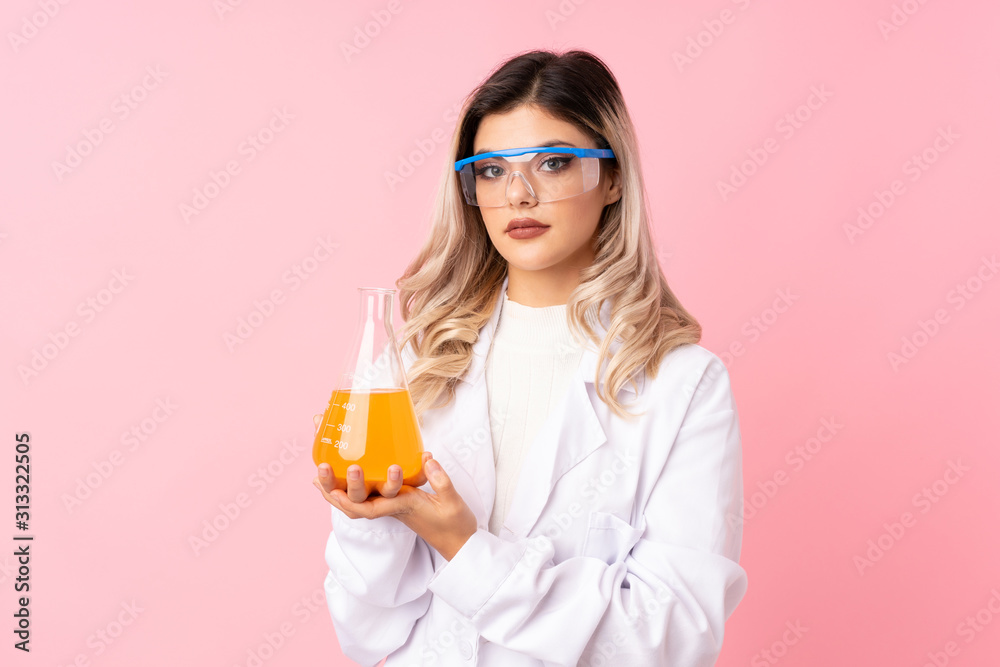 Teenager girl over isolated pink background with a scientific test tube Teenager girl over isolated pink background with a scientific test tube