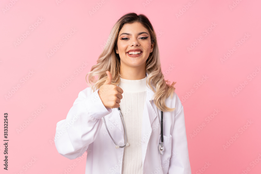 Teenager girl over isolated pink background with doctor gown and with thumb up Teenager girl over isolated pink background with doctor gown and with thumb up