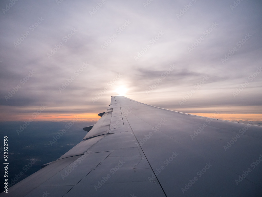 View of Sunrise Right Outside of Airplane Wing With Cloudy Skies