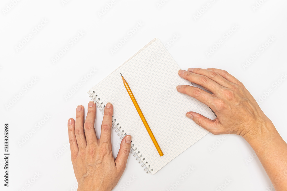 Woman hands holding a notebook and a yellow pencil ready to write, close up top view Woman hands holding a notebook and a yellow pencil ready to write, close up top view