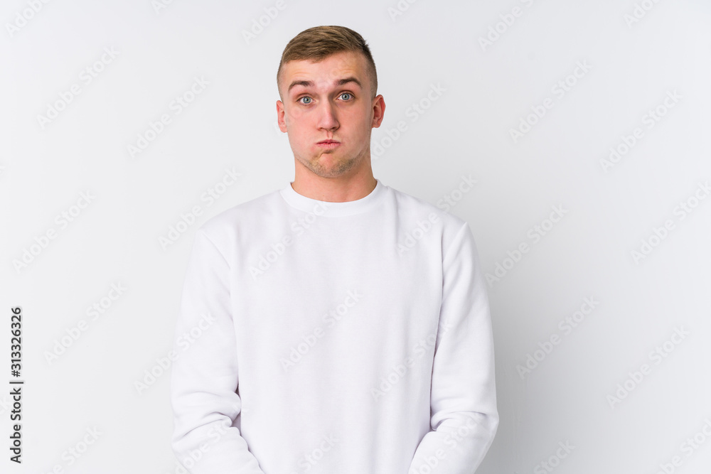 Young caucasian man on white background blows cheeks, has tired expression. Facial expression concept. Young caucasian man on white background blows cheeks, has tired expression. Facial expression concept.