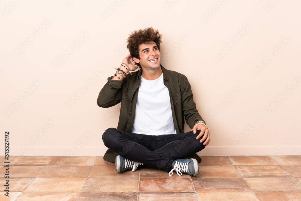 Young caucasian man sitting on the floor thinking an idea Young caucasian man sitting on the floor thinking an idea