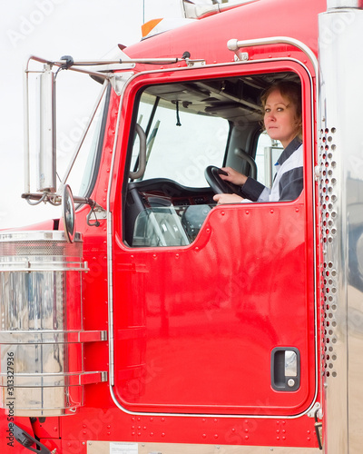 Woman Truck Driver looking out the window while driving a big rig