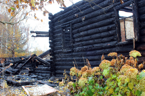 Country wooden house after a fire. Burnt walls, charred logs. The devastating effects of a fire.