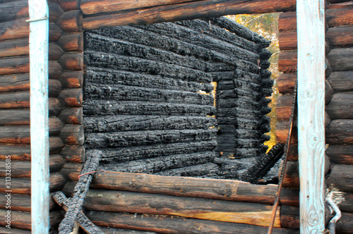 Country wooden house after a fire. Burnt walls, charred logs. The devastating effects of a fire.