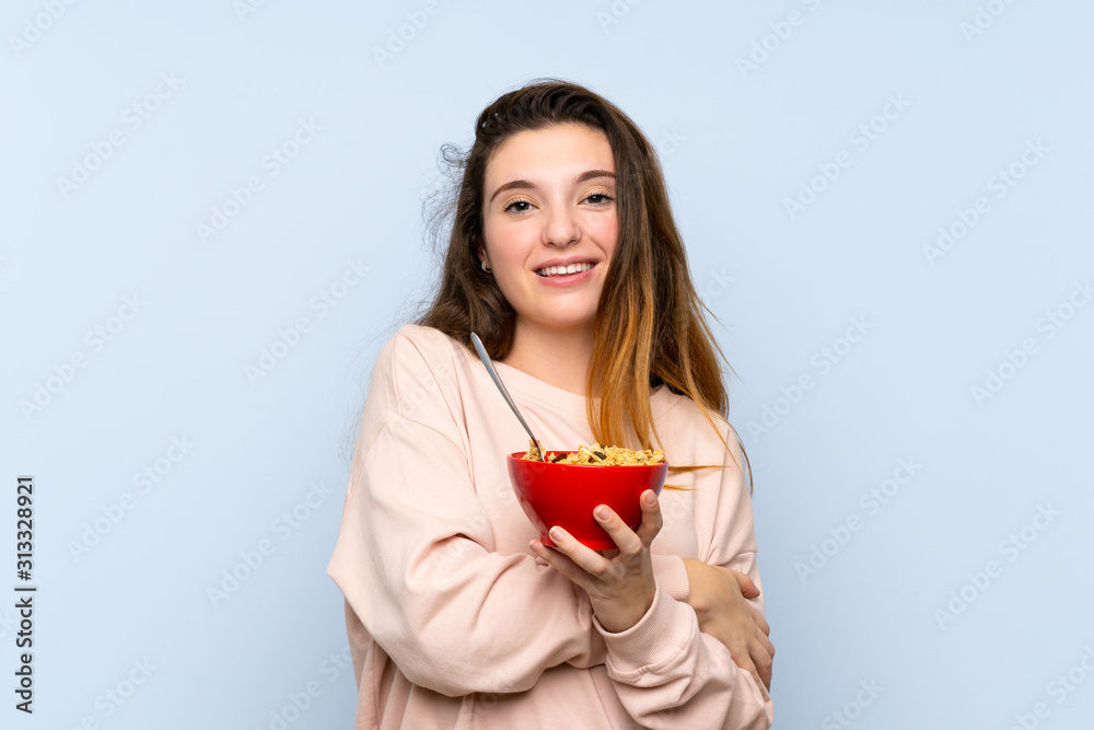 Young brunette girl over isolated blue background holding a bowl of cereals Young brunette girl over isolated blue background holding a bowl of cereals