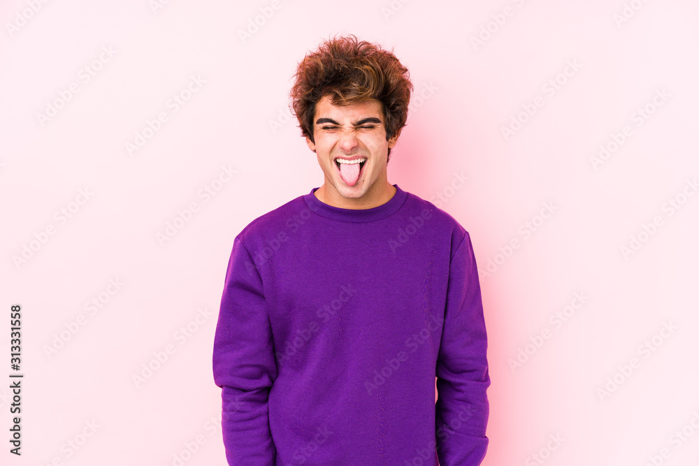 Young caucasian man against a pink background isolated funny and friendly sticking out tongue. Young caucasian man against a pink background isolated funny and friendly sticking out tongue.