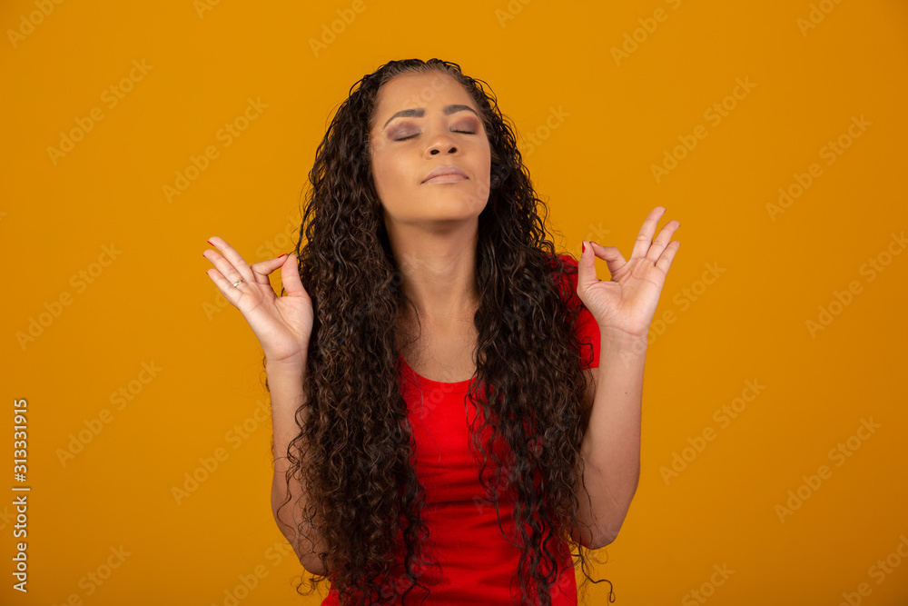 Happy, patient and relieved cute young girl with curly hair smiling relaxed and calm, show yoga mudra signs, meditating, joyful, doing breathing exercise. Brazilian girl. Happy, patient and relieved cute young girl with curly hair smiling relaxed and calm, show yoga mudra signs, meditating, joyful, doing breathing exercise. Brazilian girl.