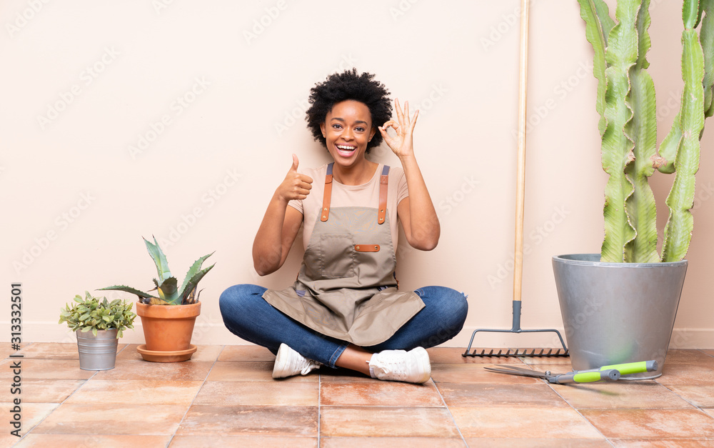 Gardener woman sitting on the floor showing ok sign and thumb up gesture Gardener woman sitting on the floor showing ok sign and thumb up gesture