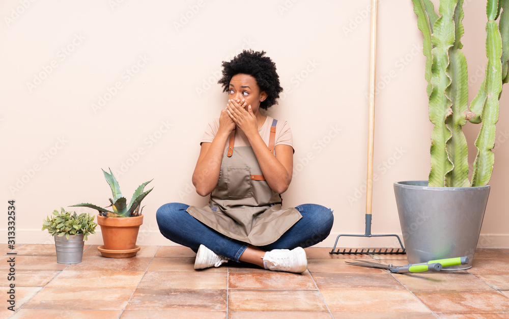 Gardener woman sitting on the floor covering mouth and looking to the side Gardener woman sitting on the floor covering mouth and looking to the side