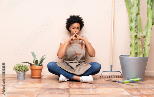 Gardener woman sitting on the floor showing a sign of silence gesture