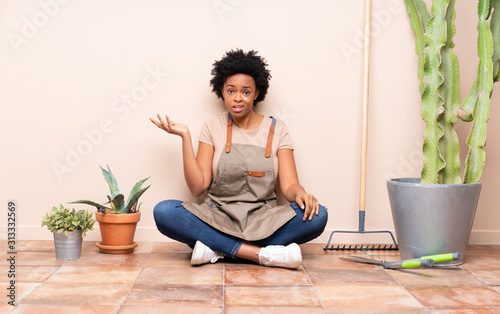 Gardener woman sitting on the floor making doubts gesture