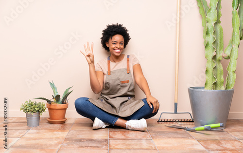 Gardener woman sitting on the floor happy and counting four with fingers