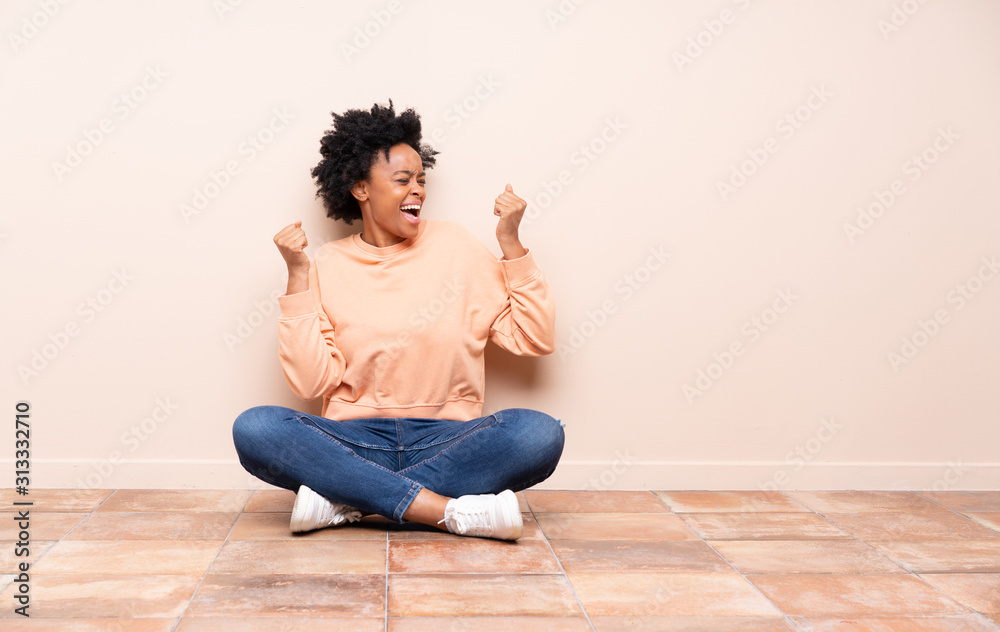 African american woman sitting on the floor celebrating a victory African american woman sitting on the floor celebrating a victory