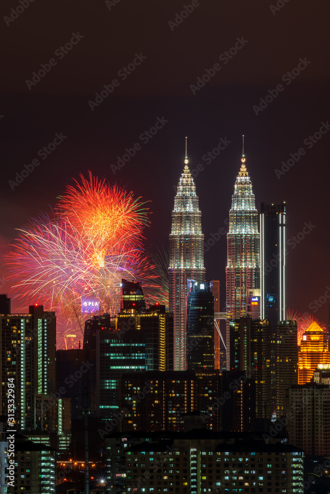 Obraz premium KUALA LUMPUR, MALAYSIA - 1ST JANUARY 2020; Fireworks explode near Malaysia's landmark Petronas Twin Towers during New Year celebrations in Kuala Lumpur.
