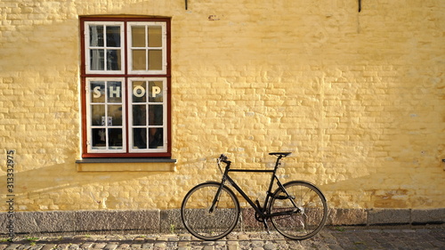 Bicycle leaning against yellow brick hipster shop