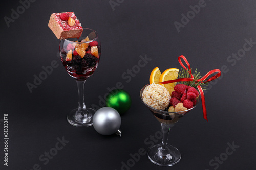 Holiday sweets and fruits in a glass and New Year's toys on a black background