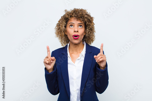 Foto young woman african american feeling awed and open mouthed pointing upwards with