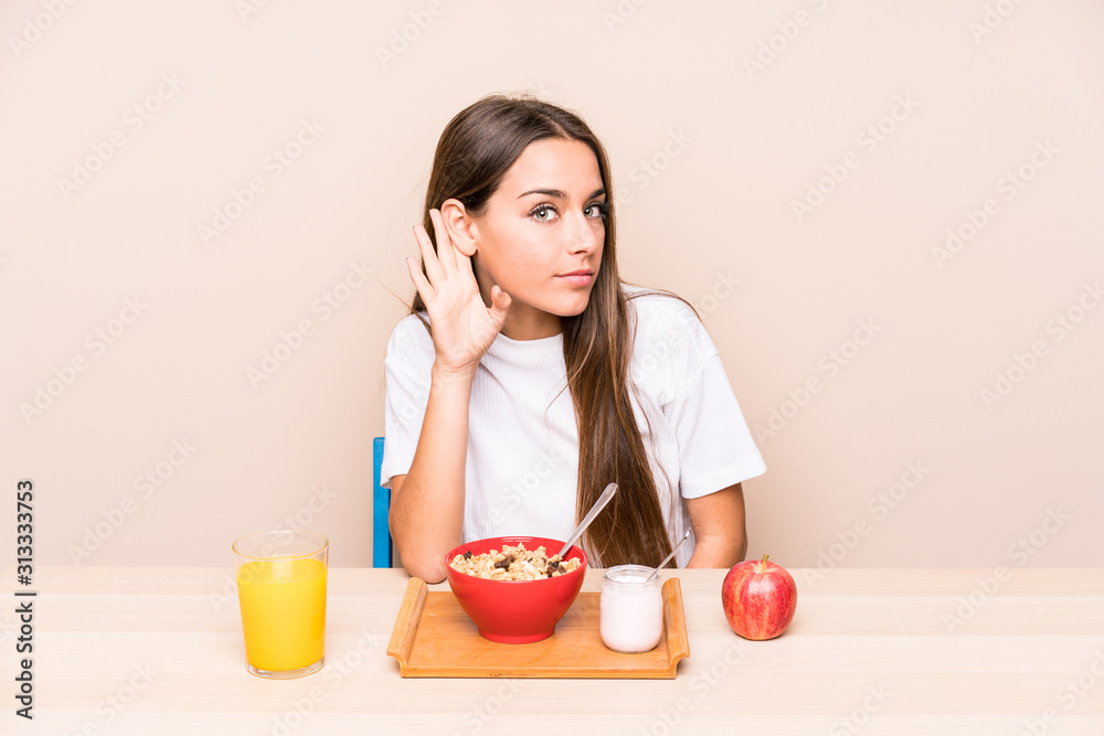 Young caucasian woman having a breakfast isolated trying to listening a gossip. Young caucasian woman having a breakfast isolated trying to listening a gossip.
