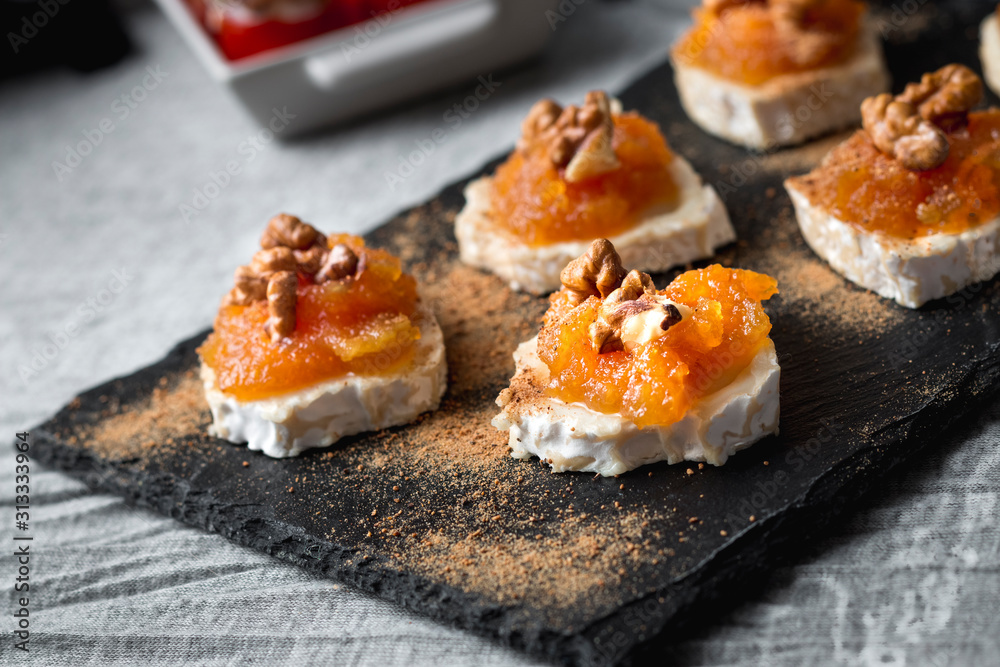 Still life of Goat roll cheese with jam and walnuts with cherry tomatoes stuffed with cheese and anchovies. Top view Still life of Goat roll cheese with jam and walnuts with cherry tomatoes stuffed with cheese and anchovies. Top view