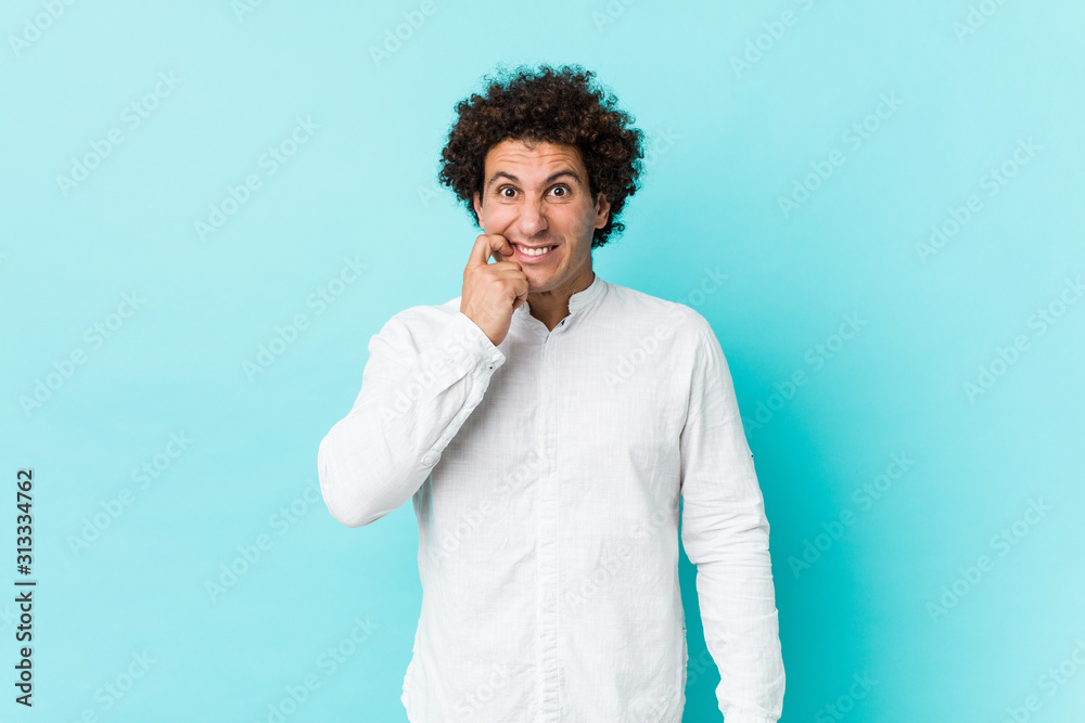 Young curly mature man wearing an elegant shirt biting fingernails, nervous and very anxious. Young curly mature man wearing an elegant shirt biting fingernails, nervous and very anxious.