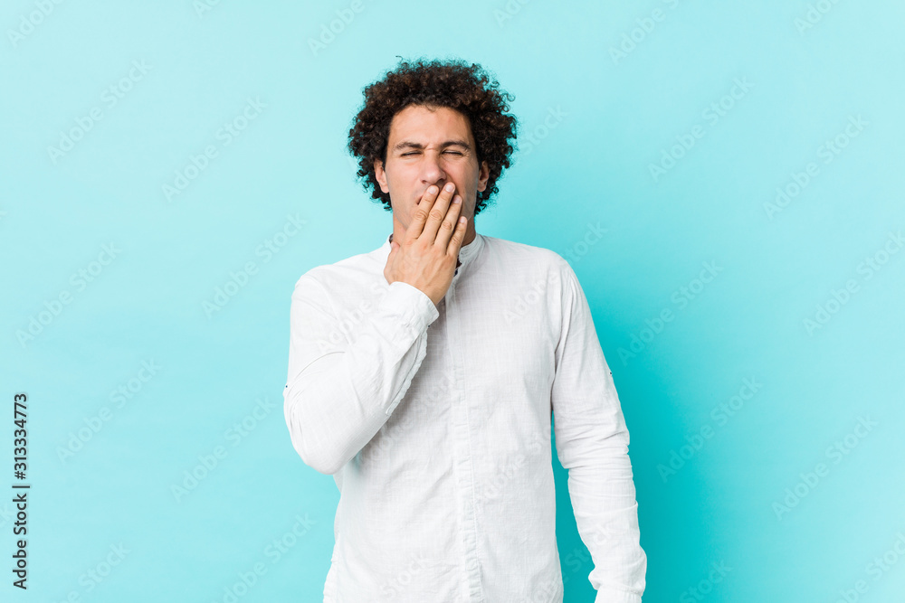 Young curly mature man wearing an elegant shirt yawning showing a tired gesture covering mouth with hand. Young curly mature man wearing an elegant shirt yawning showing a tired gesture covering mouth with hand.