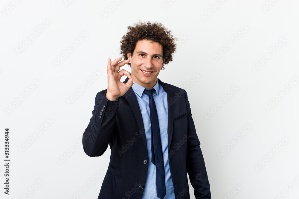 Young business curly man against white background cheerful and confident showing ok gesture. Young business curly man against white background cheerful and confident showing ok gesture.