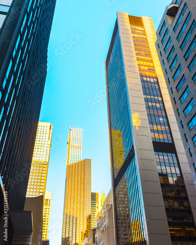 Bottom up Street view on Financial District of Lower Manhattan, New York City, NYC, USA. Skyscrapers tall glass buildings United States of America. Blue sky on background. Empty place for copy space.