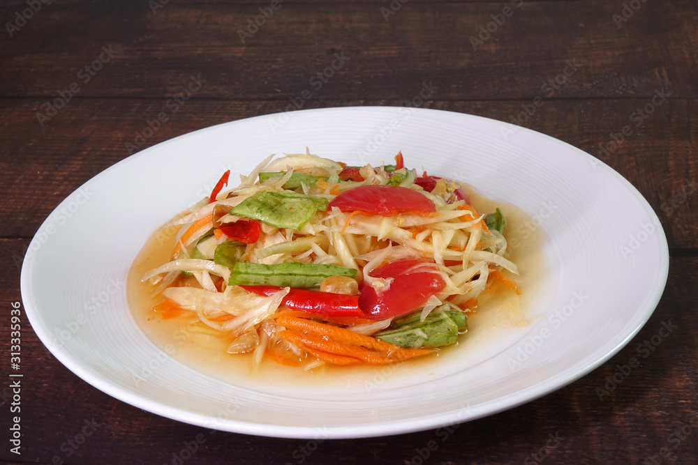 Somtam or Spicy green papaya salad, Thai cuisine. Green  papaya salad is a spicy salad made from shredded unripe papaya. Originating from ethnic Lao people, it is also eaten throughout Southeast Asia.